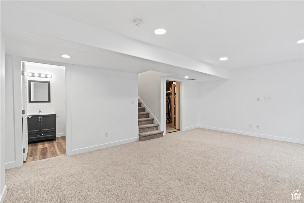 Finished below grade area with light colored carpet, stairs, baseboards, and recessed lighting