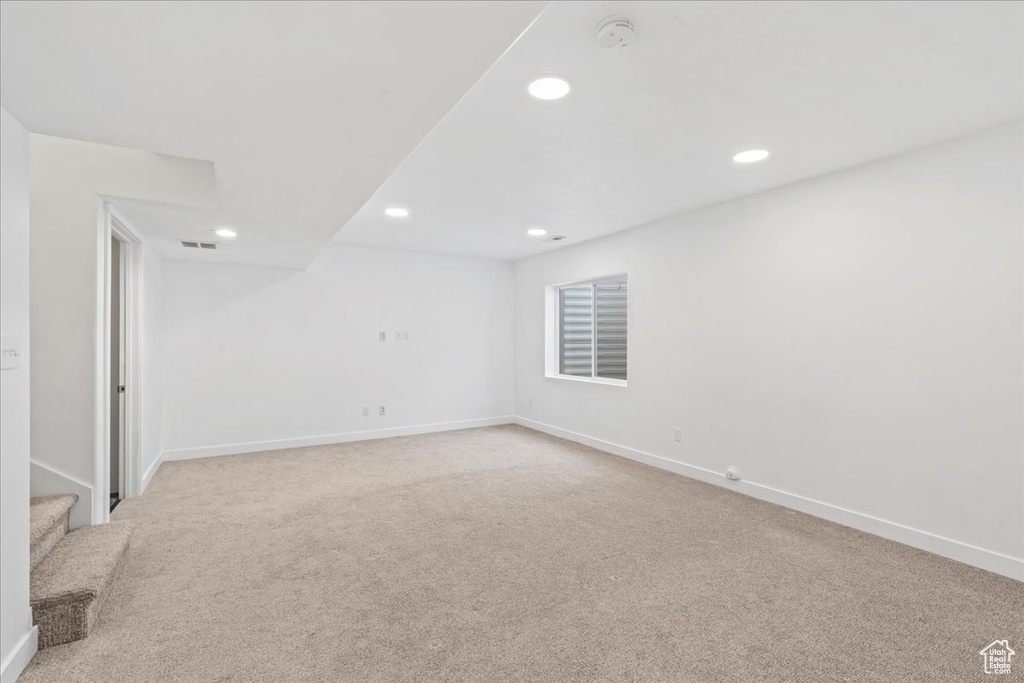 Empty room with light colored carpet, recessed lighting, baseboards, stairs, and a smoke detector