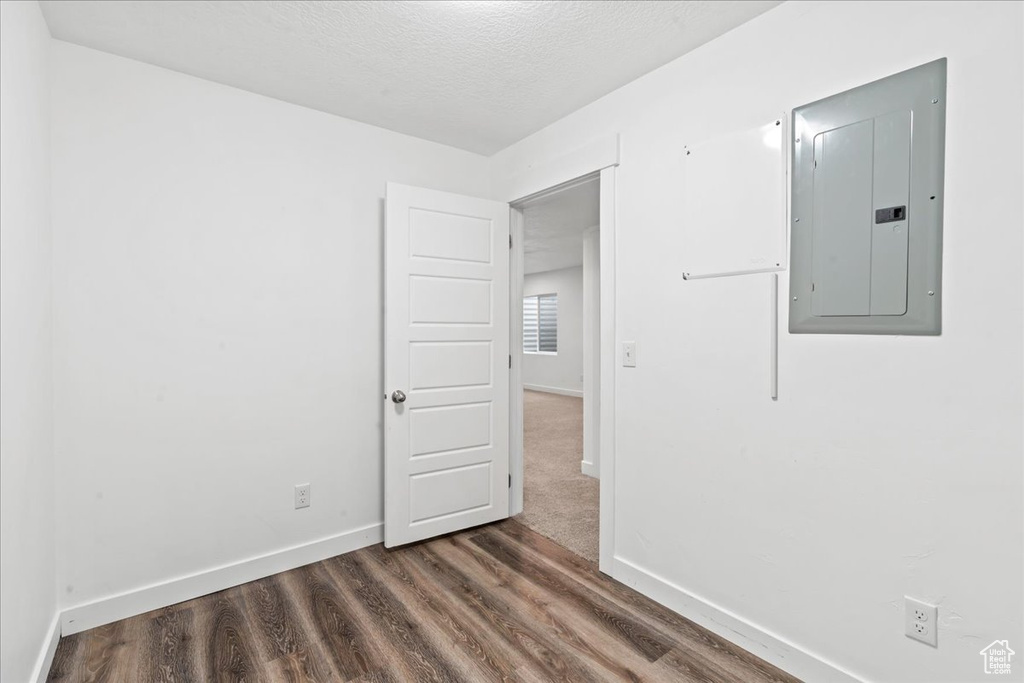 Unfurnished room featuring electric panel, wood finished floors, baseboards, and a textured ceiling