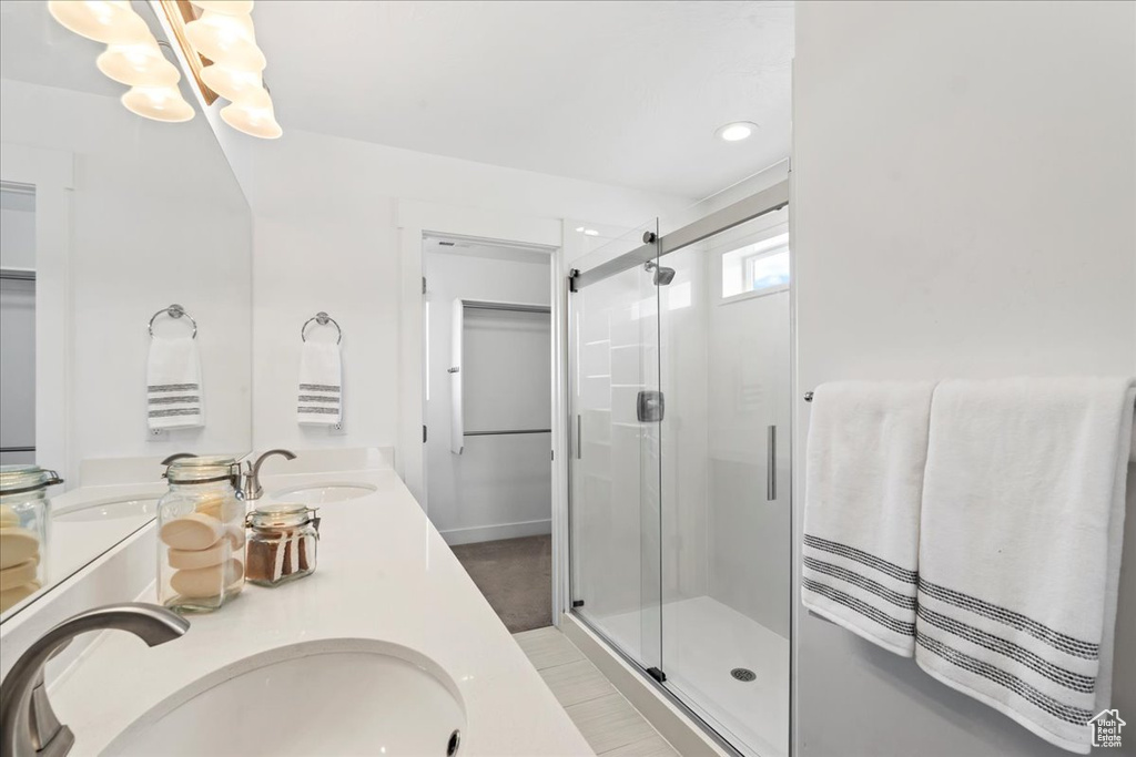 Full bathroom with a shower stall, a chandelier, and double vanity