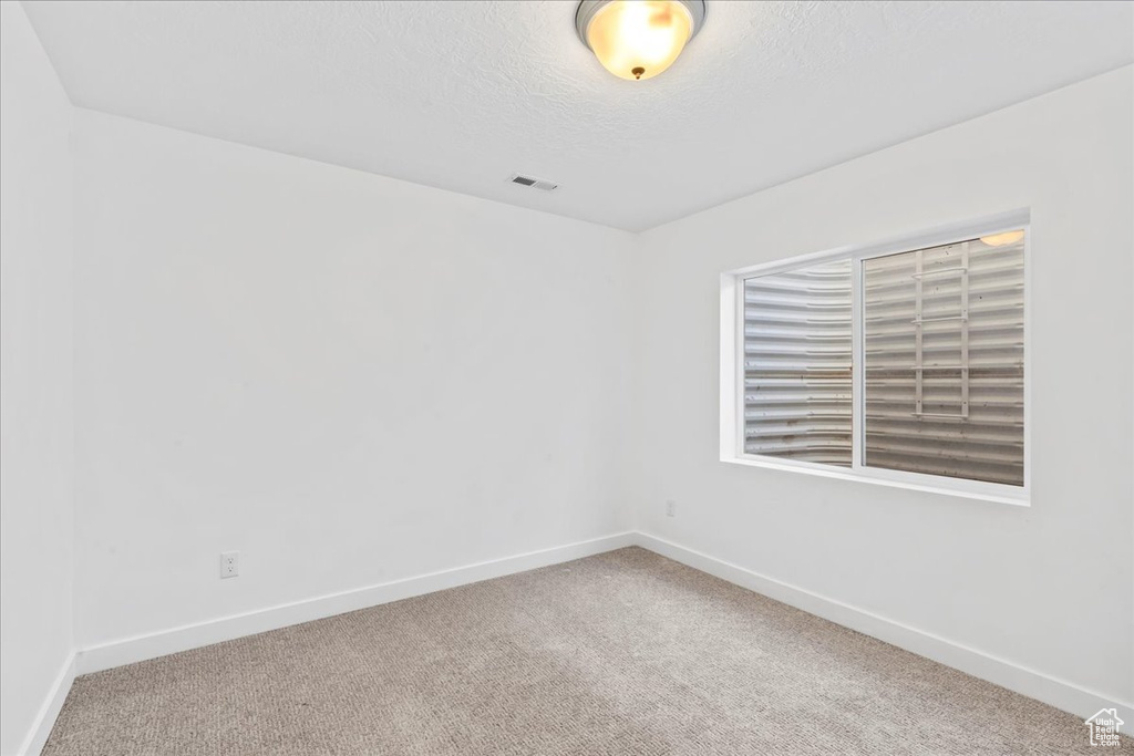 Carpeted spare room featuring baseboards and a textured ceiling