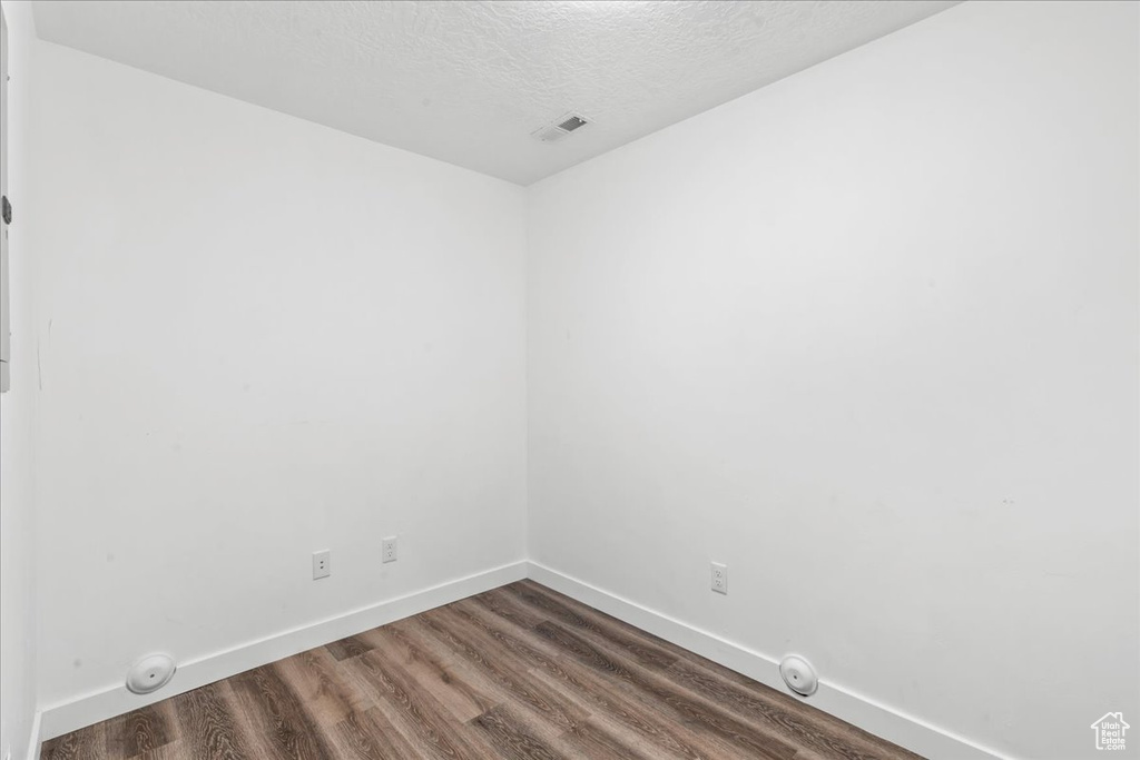 Unfurnished room with dark wood finished floors, baseboards, and a textured ceiling