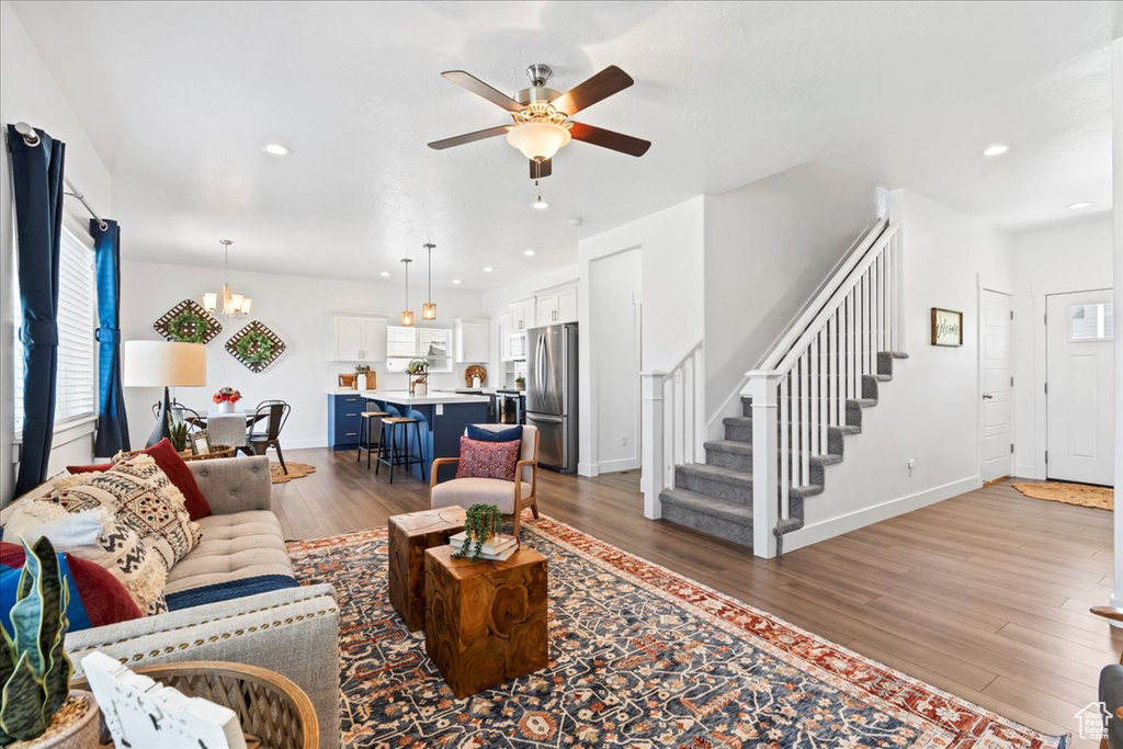 Living area featuring wood finished floors, a ceiling fan, stairs, a chandelier, and recessed lighting