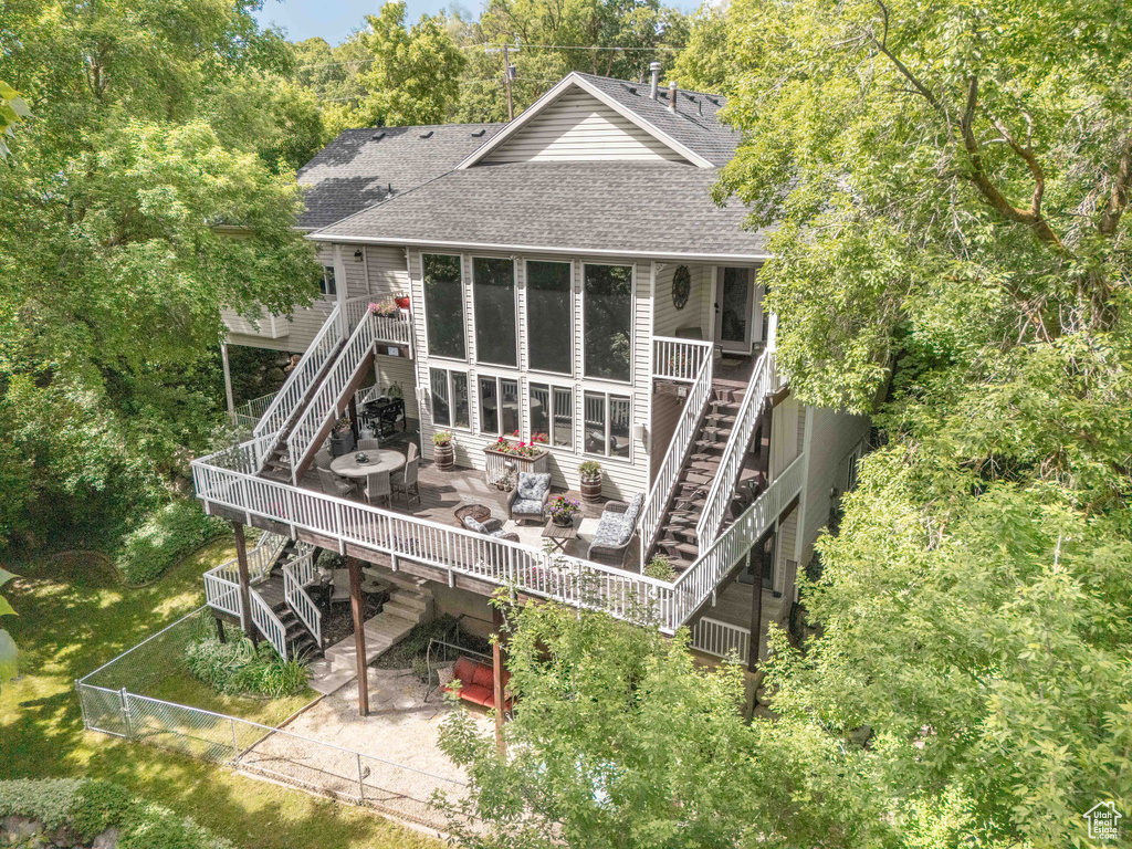 Back of property featuring stairway, roof with shingles, a wooden deck, and a fenced backyard