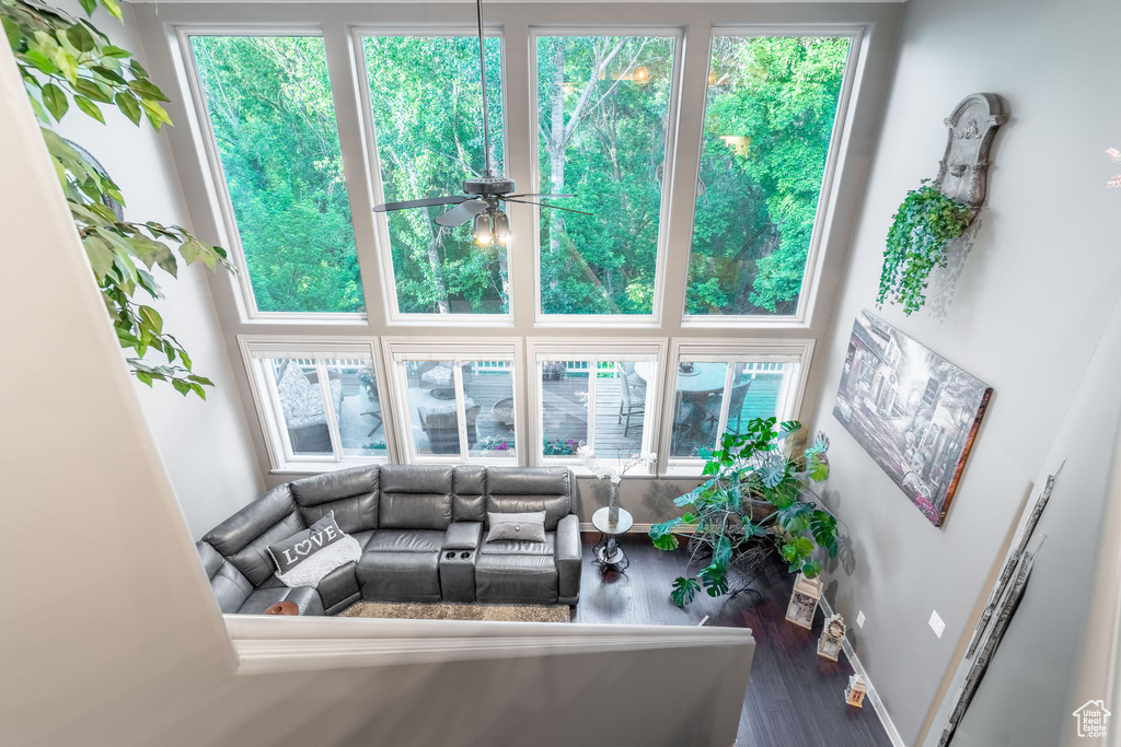 Living area with wood finished floors, a ceiling fan, healthy amount of natural light, and baseboards