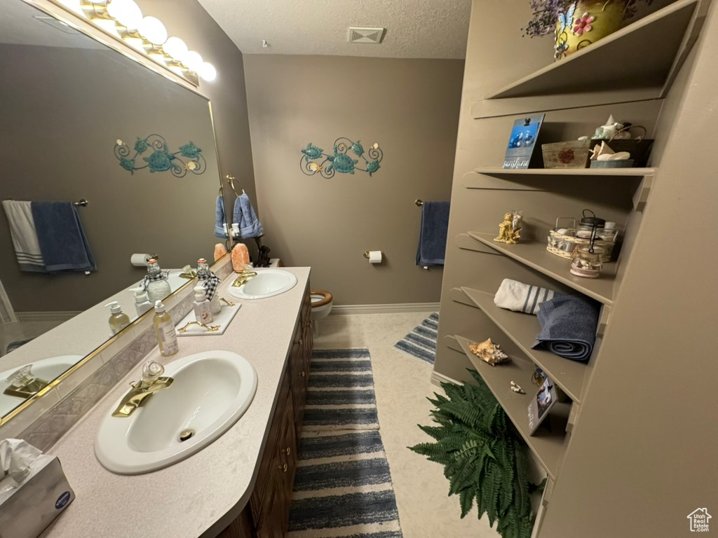 Full bathroom with double vanity and a textured ceiling