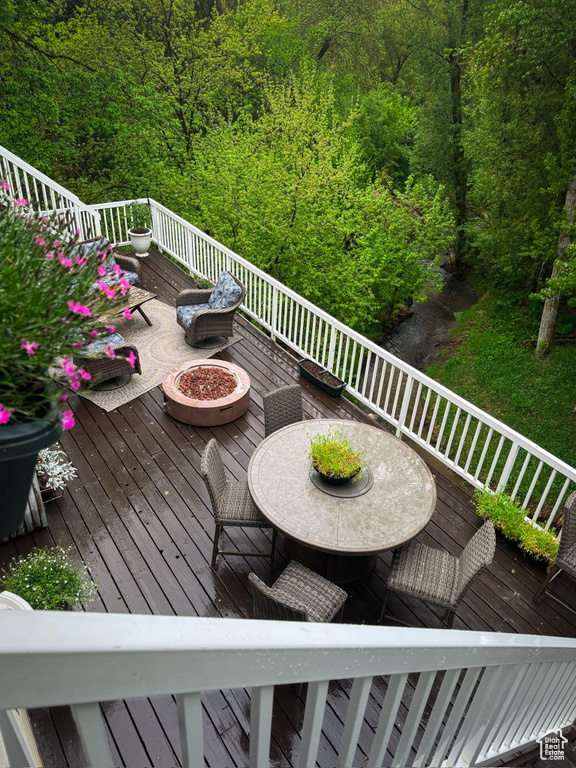 Wooden deck featuring a forest view and an outdoor fire pit