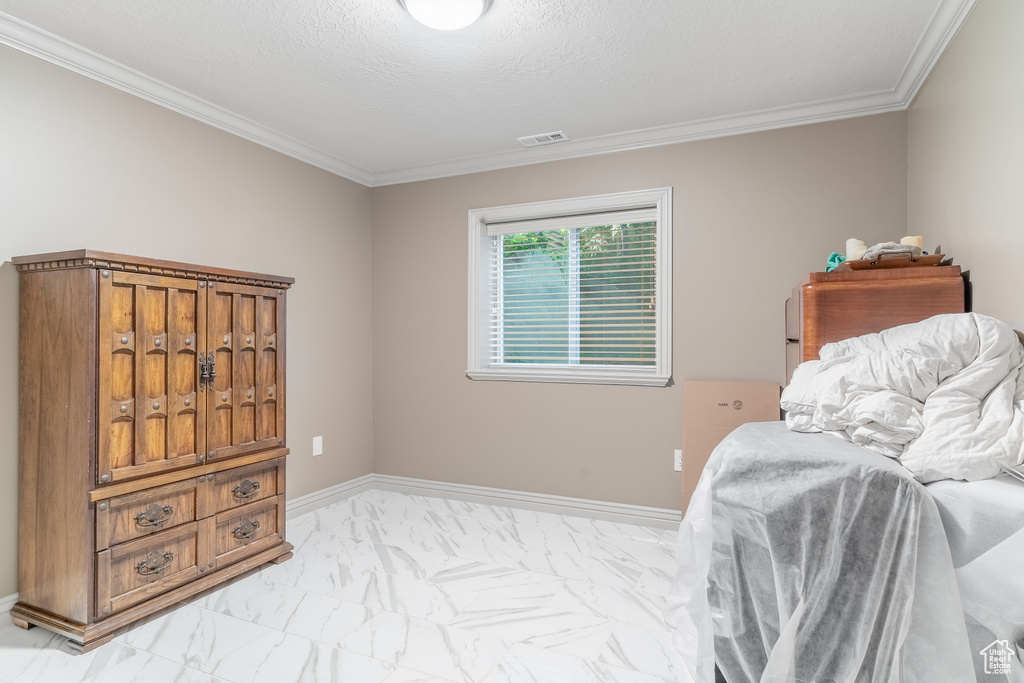 Bedroom featuring light marble finish floors and ornamental molding