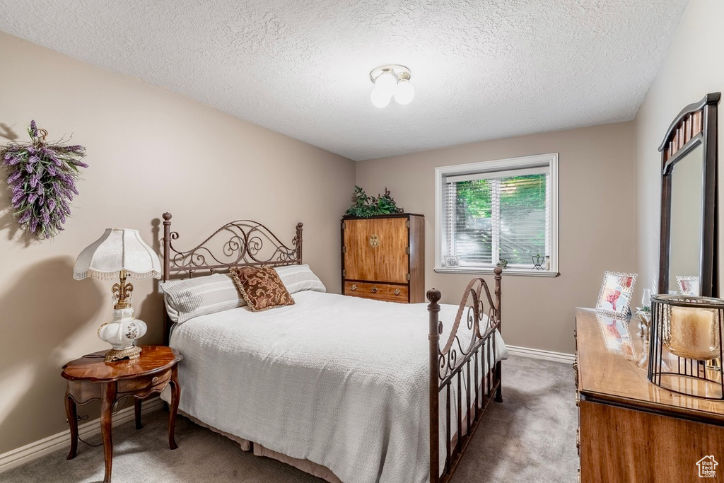 Carpeted bedroom featuring baseboards and a textured ceiling