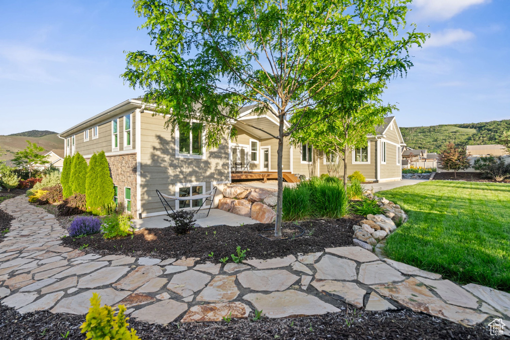 View of front of house featuring a patio, a front lawn, and a mountain view