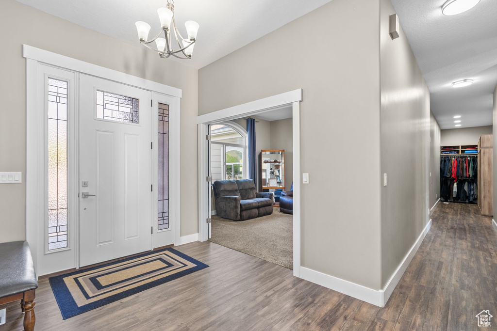 Foyer entrance with a chandelier, wood finished floors, and baseboards