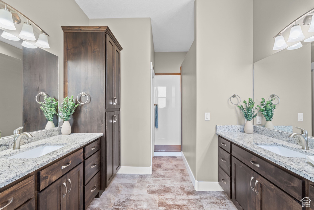 Full bath featuring two vanities and baseboards