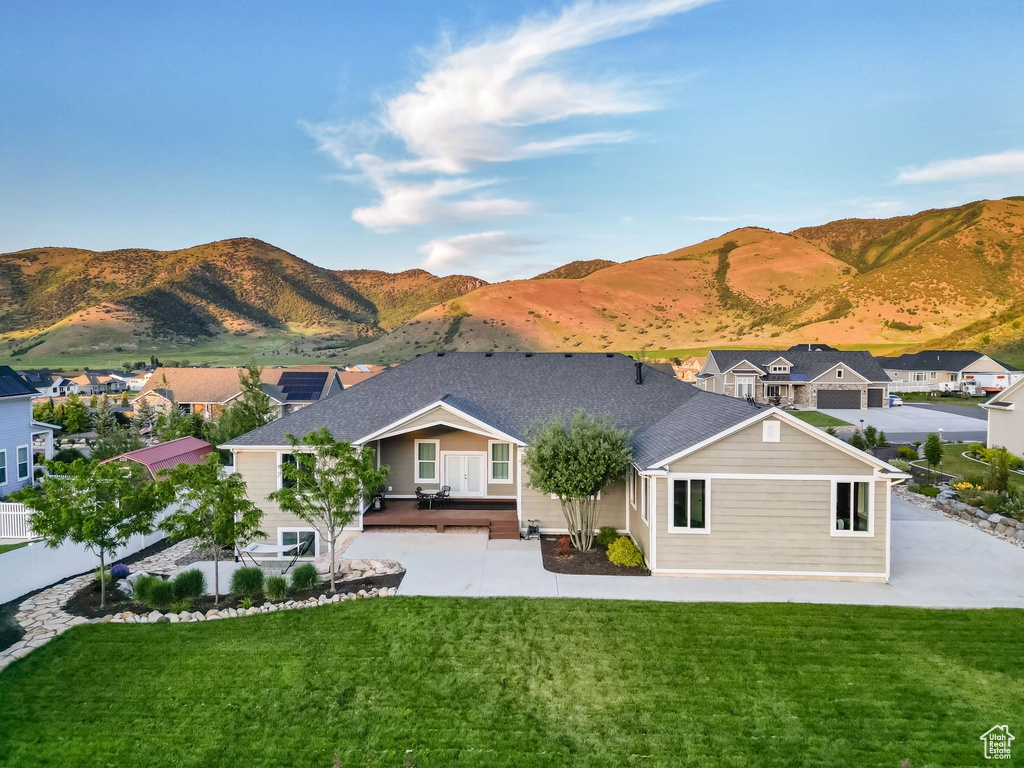 Rear view of house with a patio area, a yard, and a mountain view