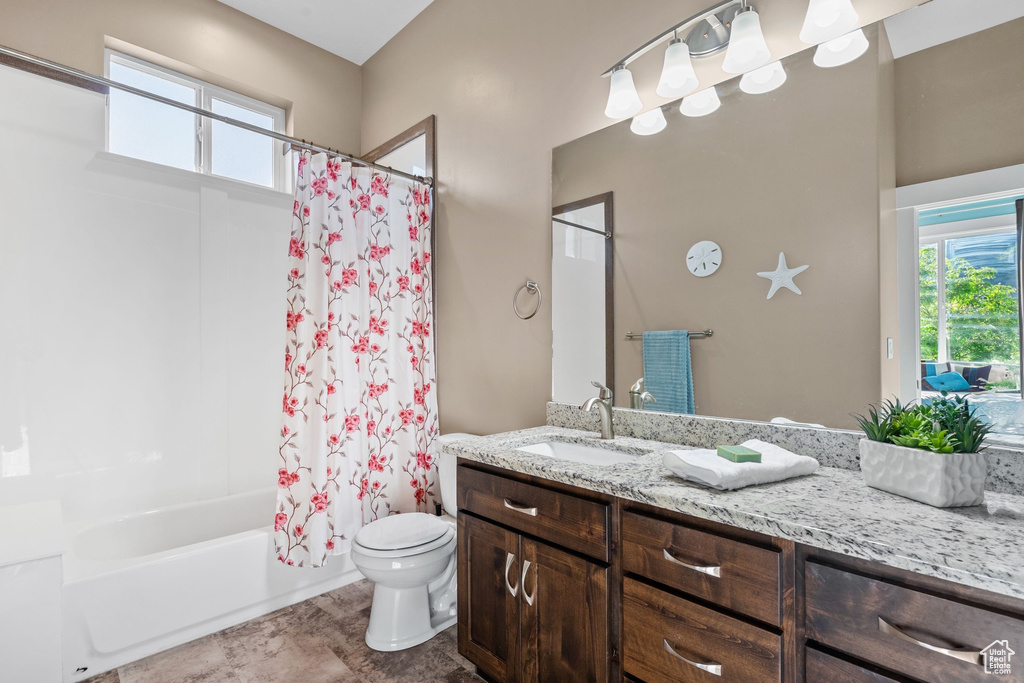 Full bathroom featuring toilet, vanity, and shower / bathtub combination with curtain
