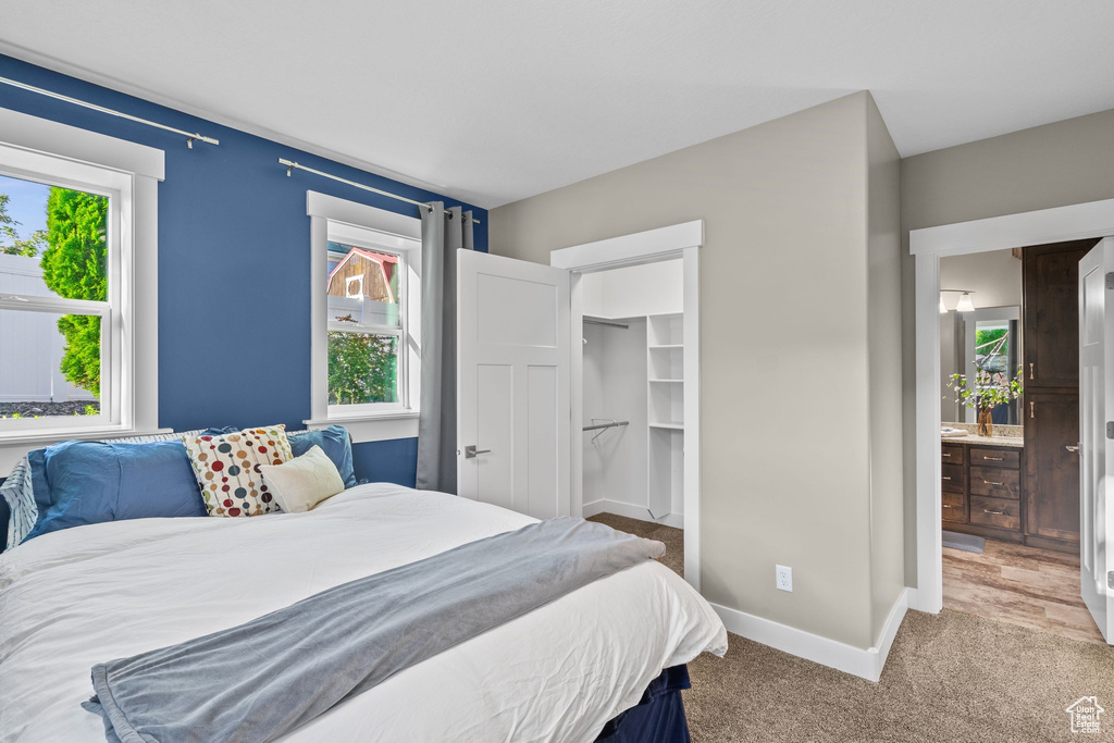Bedroom with light colored carpet, multiple windows, and baseboards