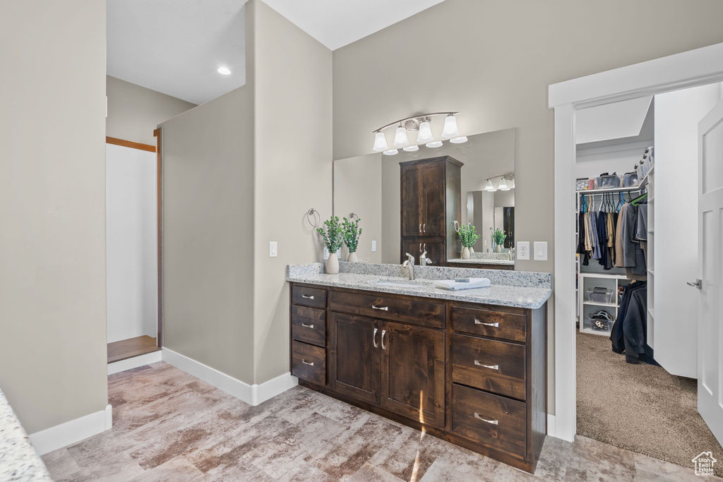 Bathroom with vanity, a spacious closet, baseboards, and recessed lighting