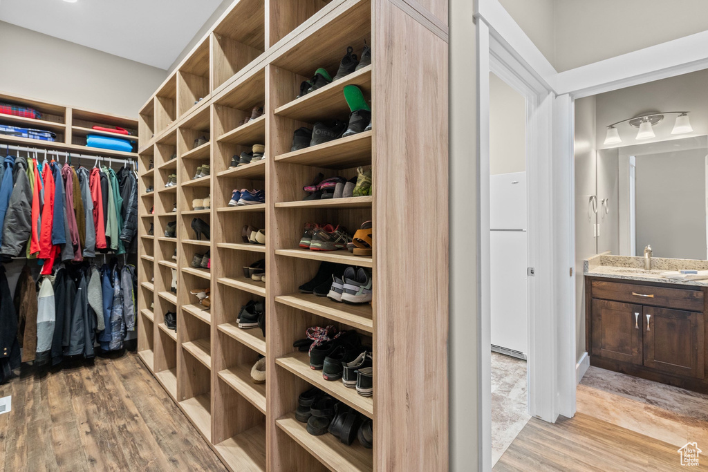 Walk in closet with light wood-style floors and a sink