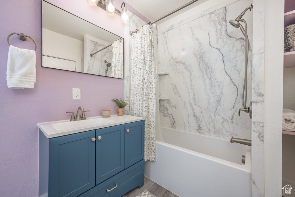 Full bathroom with vanity, shower / bath combo, and wood finished floors