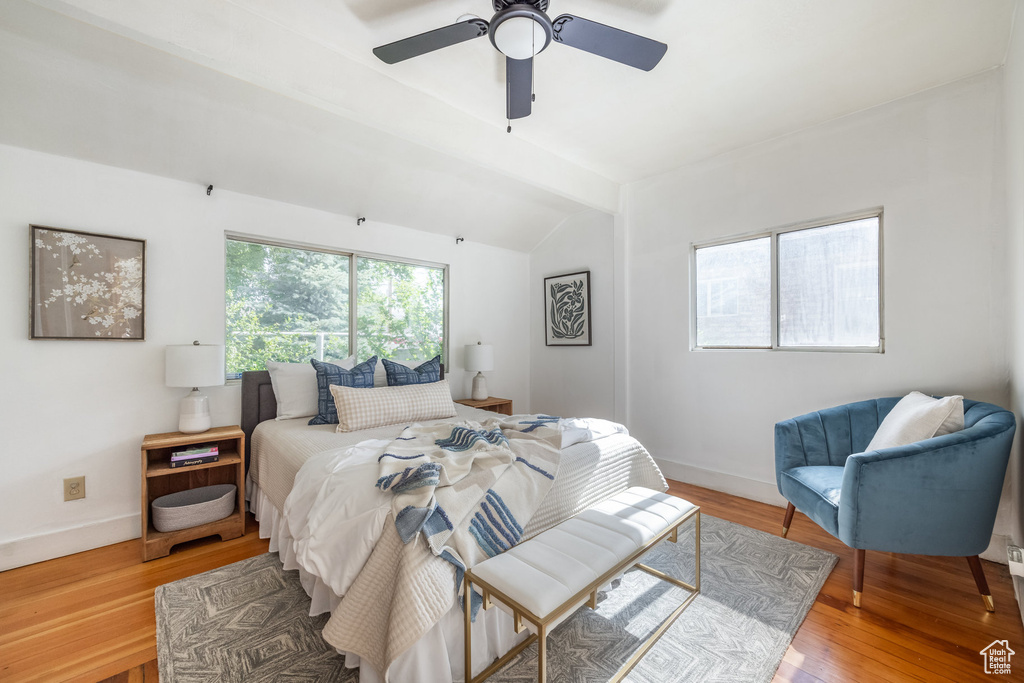Bedroom with vaulted ceiling, light wood-type flooring, baseboards, and a ceiling fan