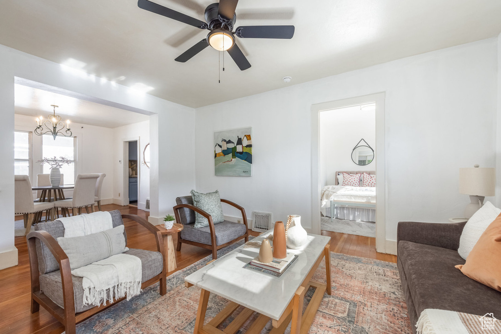Living area featuring a chandelier, light wood-style flooring, ceiling fan, and baseboards