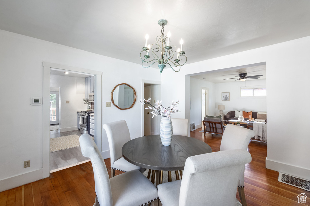 Dining room featuring wood finished floors, a chandelier, ceiling fan, and baseboards
