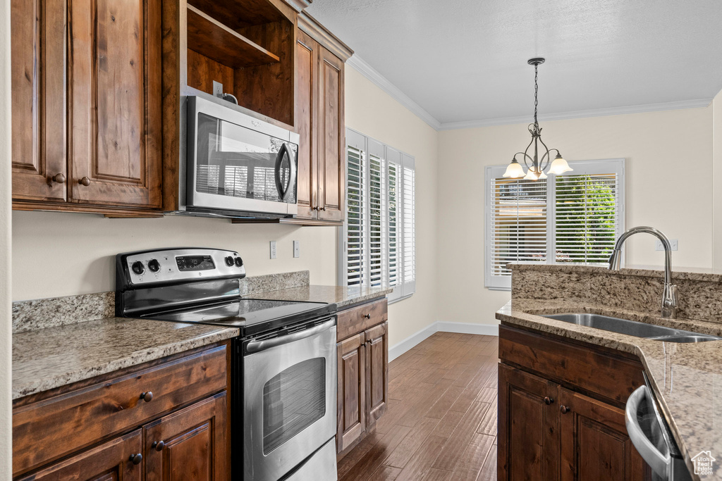 Kitchen with appliances with stainless steel finishes, a sink, plenty of natural light, a chandelier, and ornamental molding