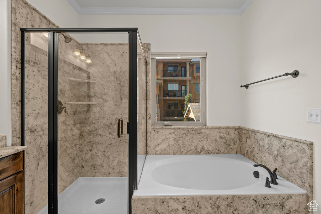 Bathroom featuring a garden tub, a shower stall, vanity, and ornamental molding