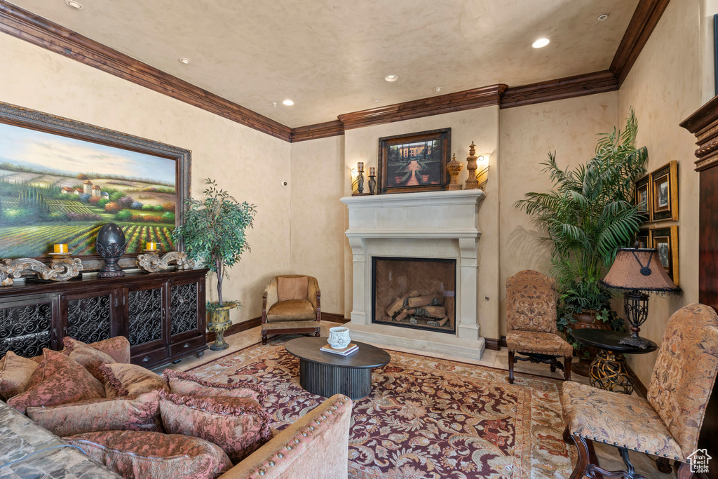 Living room featuring a fireplace with raised hearth, baseboards, recessed lighting, and ornamental molding