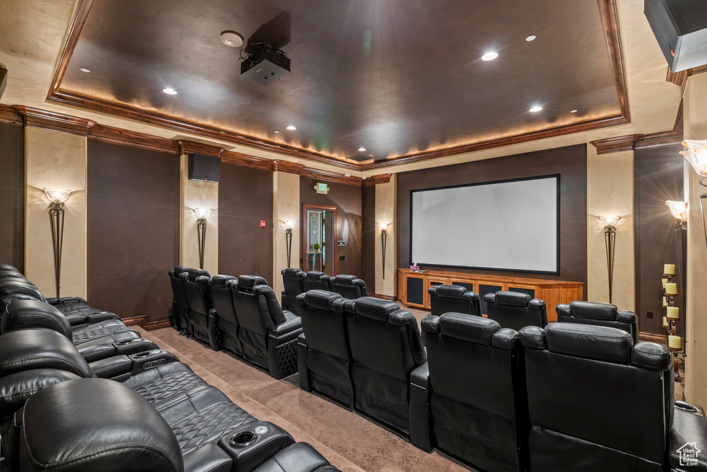 Home theater featuring a tray ceiling, carpet flooring, and ornamental molding