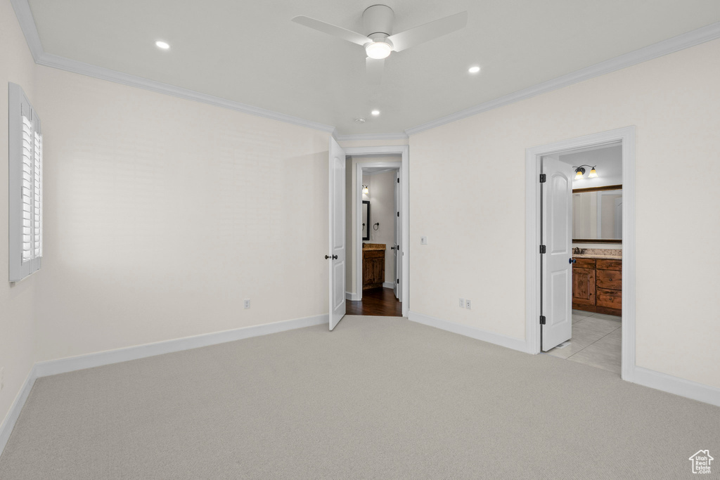 Unfurnished bedroom featuring crown molding, light colored carpet, baseboards, ensuite bath, and recessed lighting