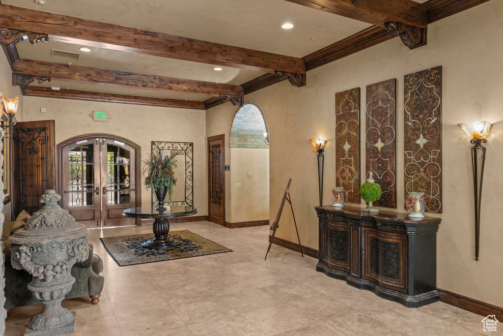 Foyer with arched walkways, beam ceiling, french doors, baseboards, and recessed lighting