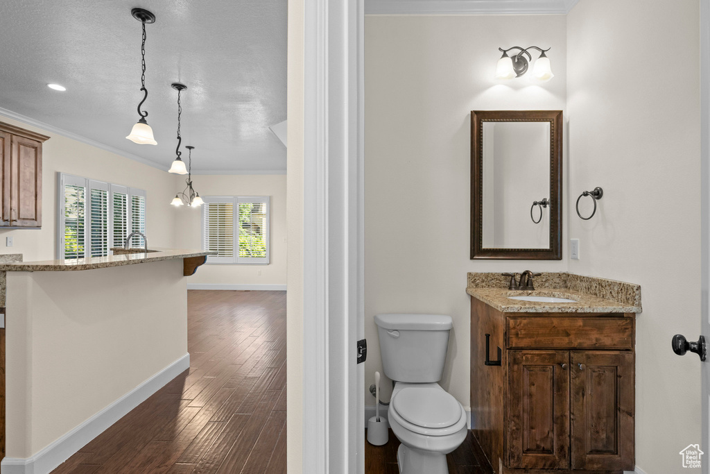 Bathroom featuring vanity, crown molding, baseboards, wood finished floors, and toilet