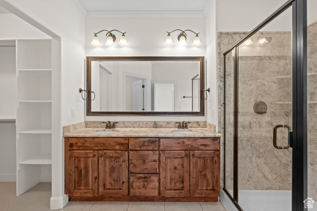 Full bath with ornamental molding, a shower stall, and double vanity
