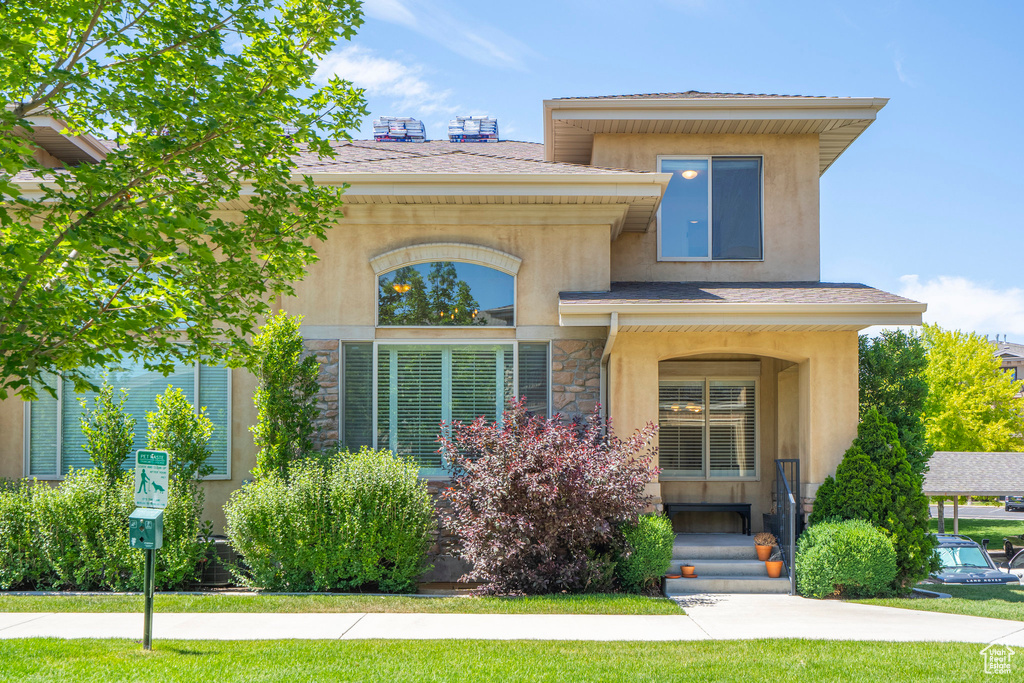 View of front of property featuring stucco siding, stone siding, and a front lawn