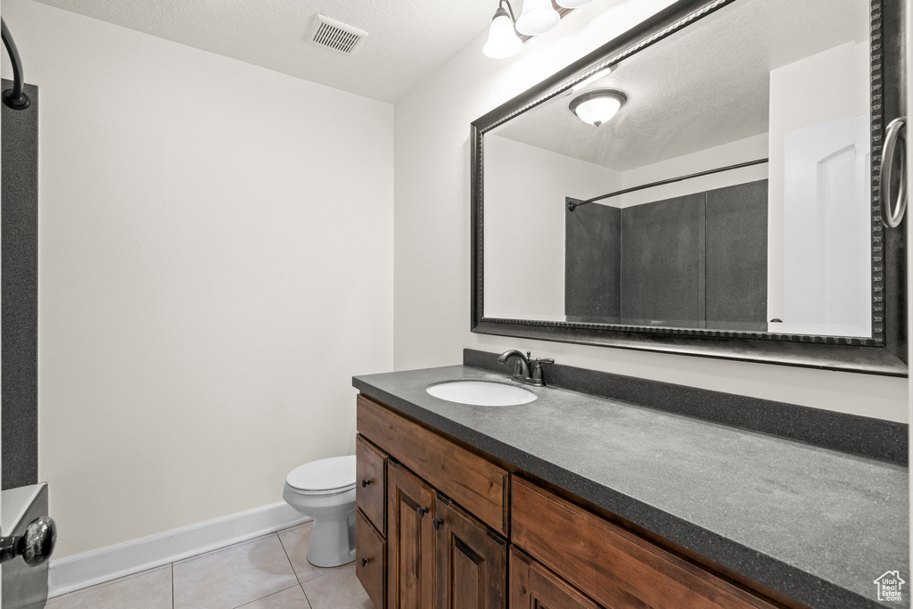 Full bathroom with tile patterned flooring, vanity, toilet, a shower, and baseboards