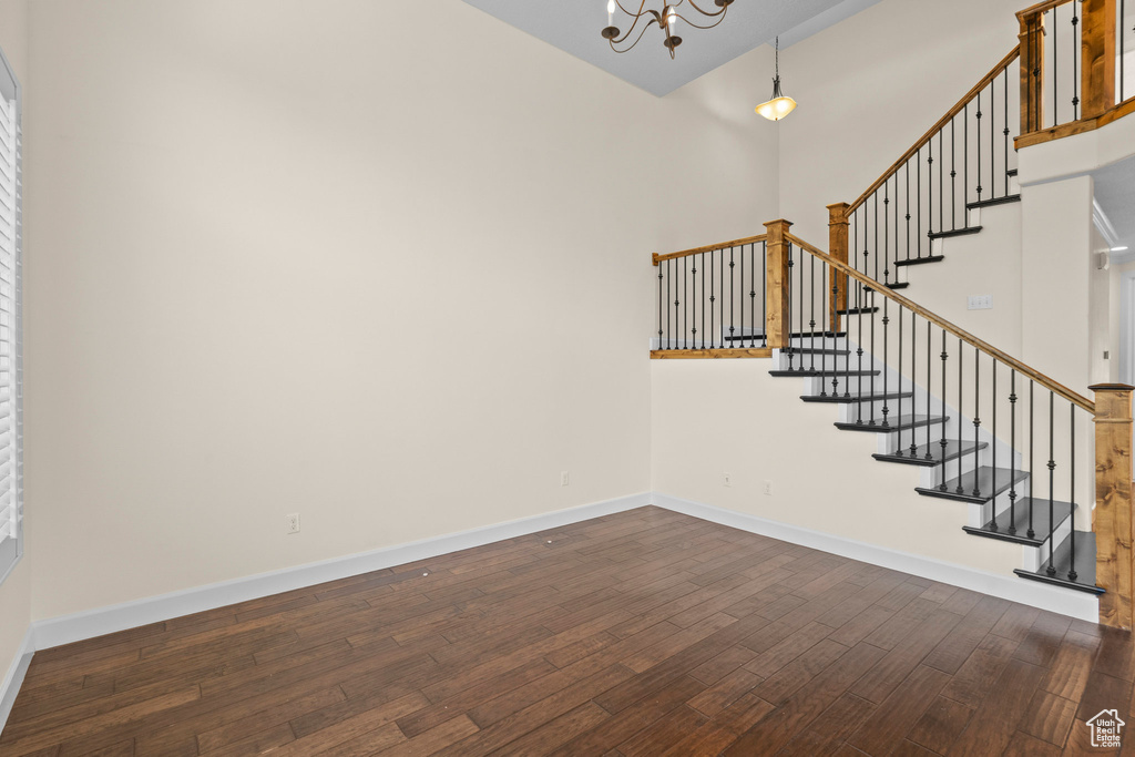 Stairway featuring wood-type flooring, a towering ceiling, a chandelier, and baseboards