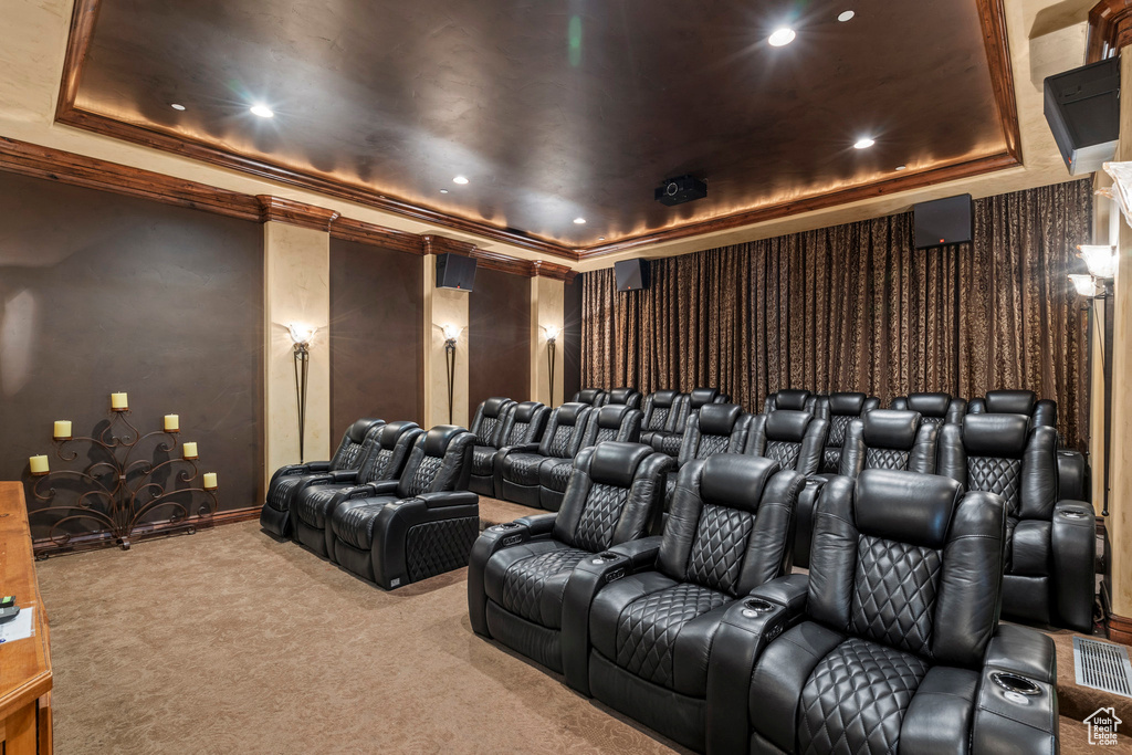 Carpeted home theater room with a raised ceiling, ornamental molding, baseboards, and recessed lighting