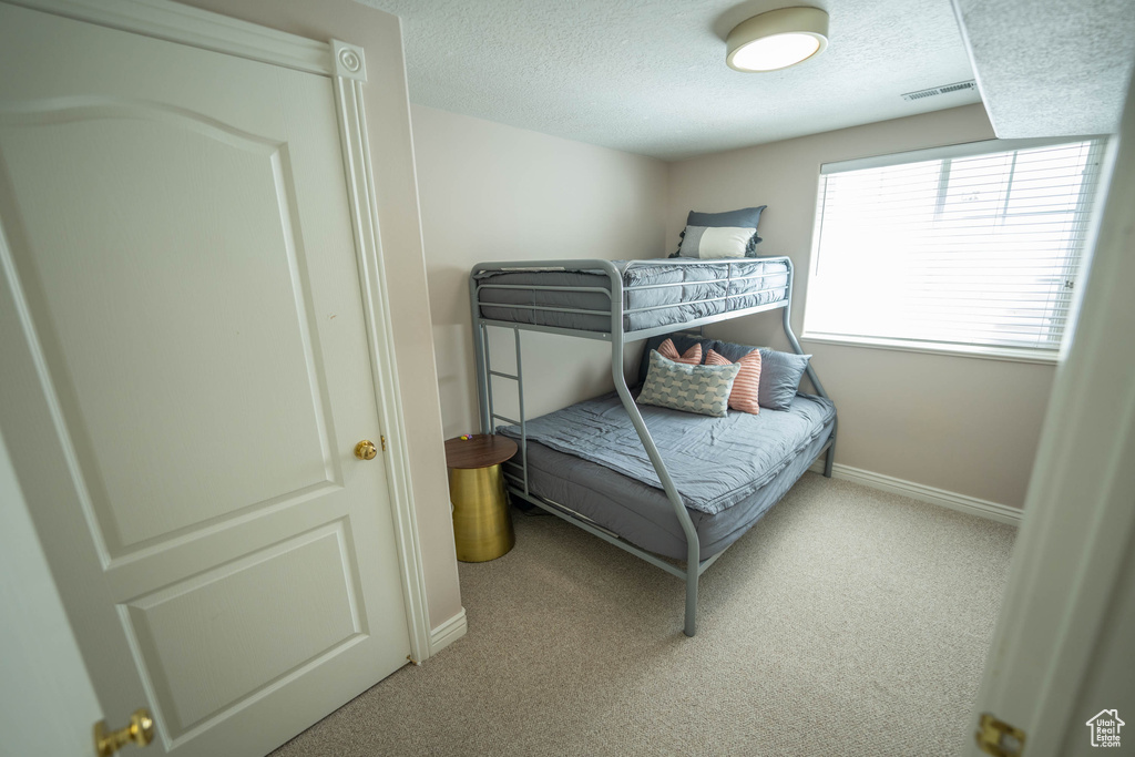Carpeted bedroom featuring a textured ceiling and baseboards