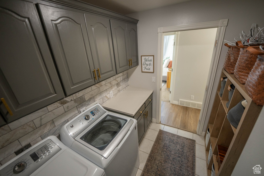 Washroom with washer and clothes dryer, cabinet space, and light tile patterned floors