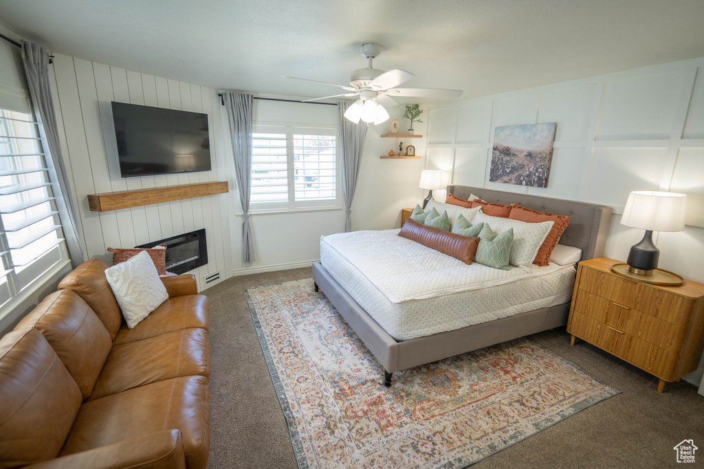 Bedroom with carpet floors, a ceiling fan, and a fireplace
