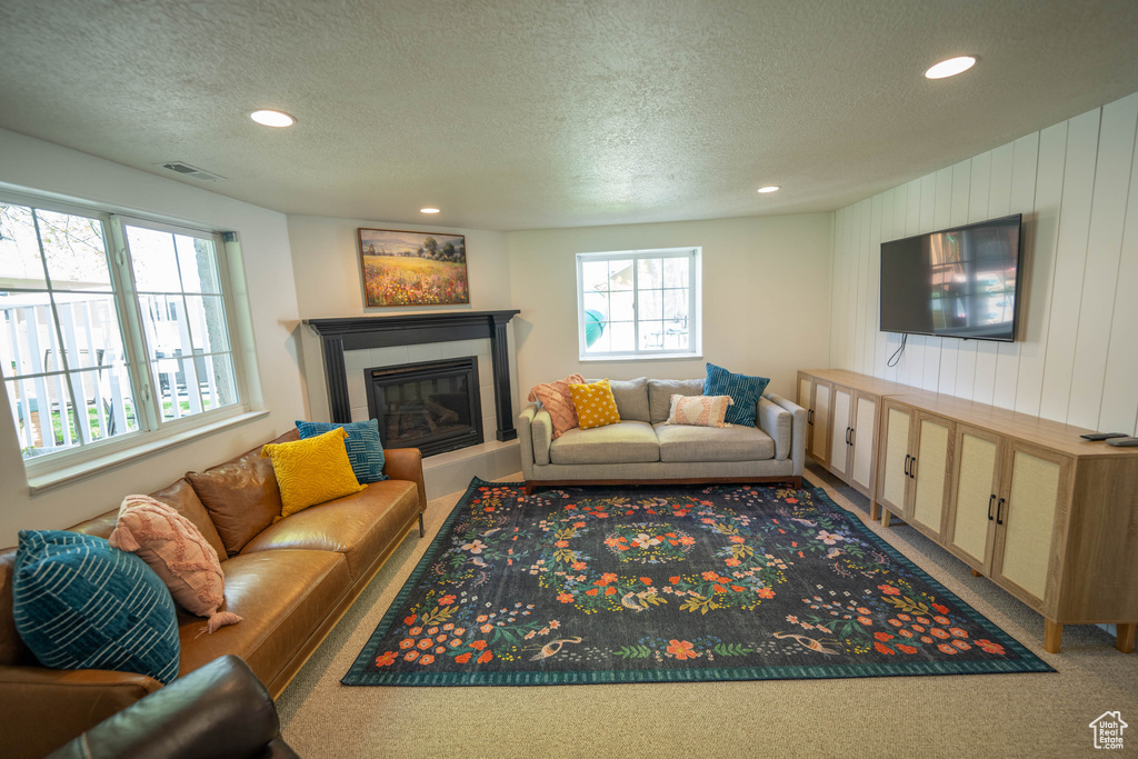 Living area with a textured ceiling, recessed lighting, a fireplace, and carpet