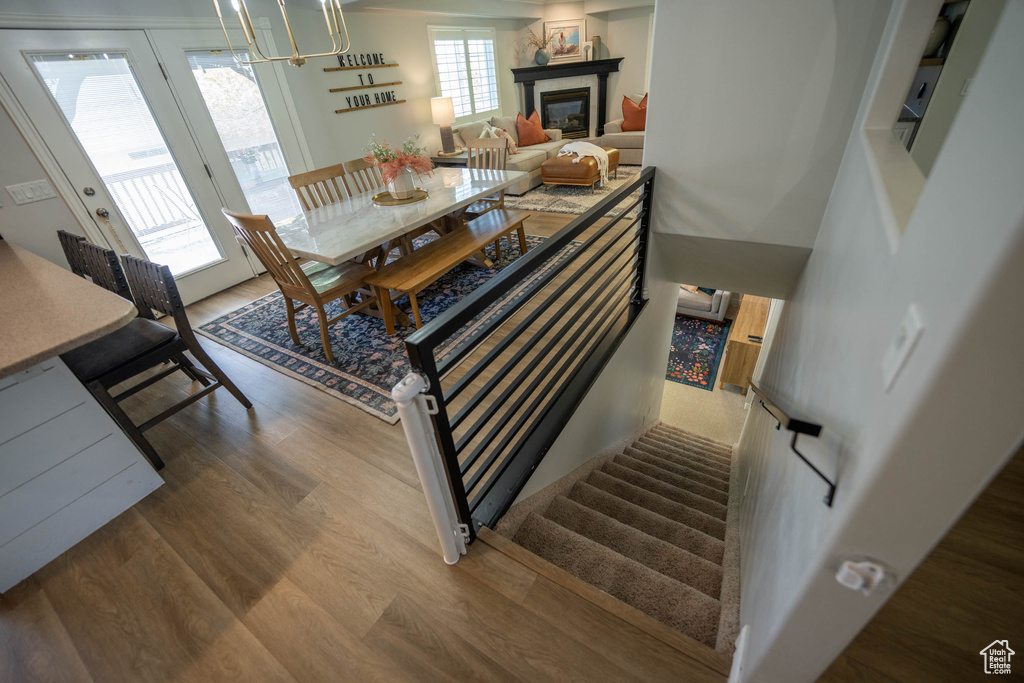 Staircase with wood finished floors, a chandelier, and a glass covered fireplace