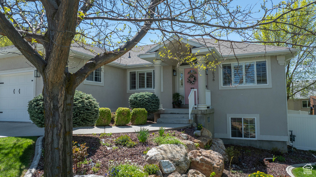 View of front of house with stucco siding, an attached garage, and a shingled roof