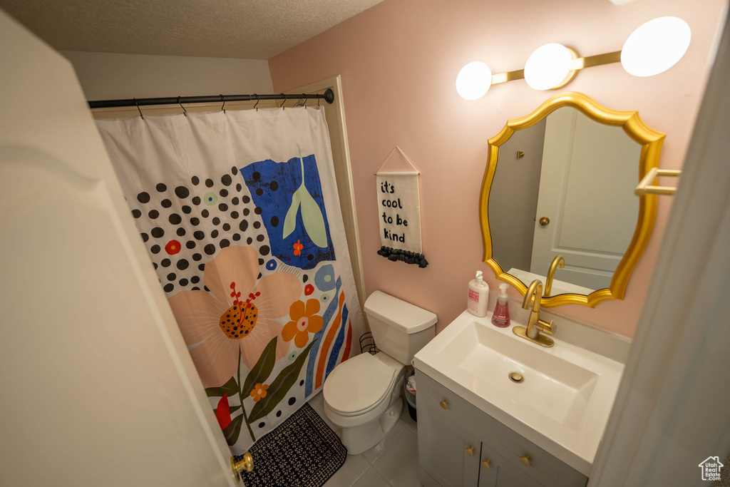 Bathroom featuring toilet, vanity, tile patterned floors, curtained shower, and a textured ceiling