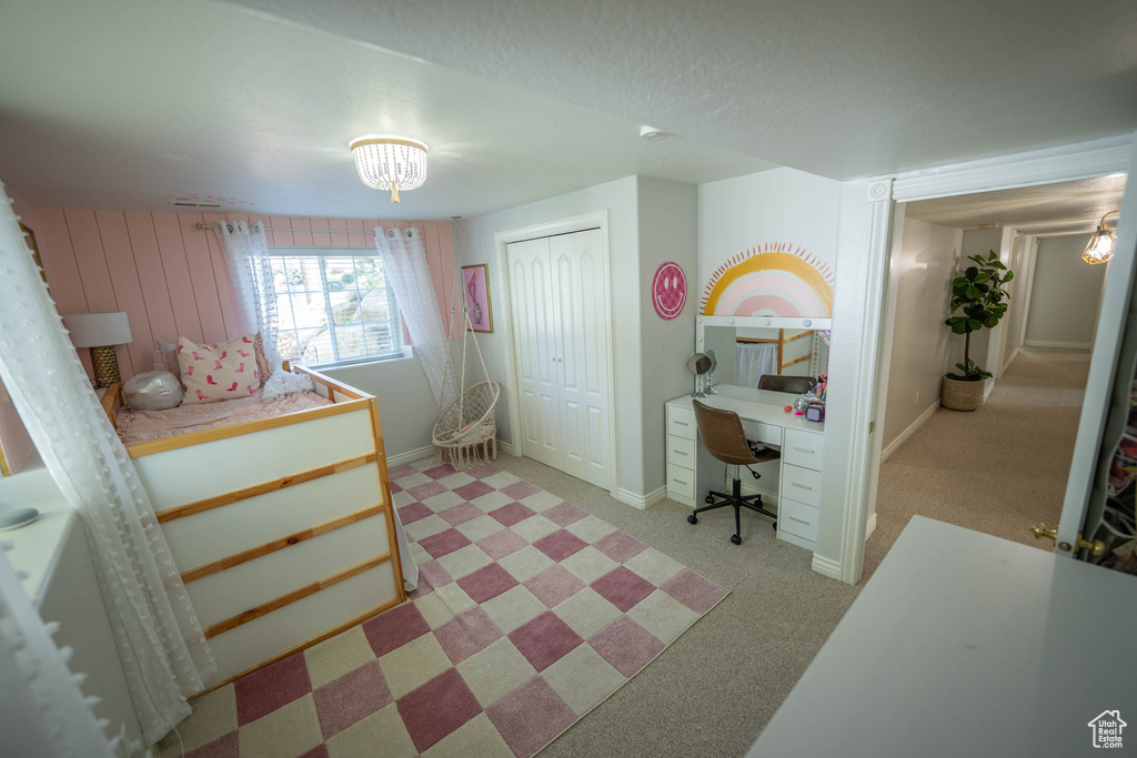 Bedroom with an office area, a closet, baseboards, and light colored carpet