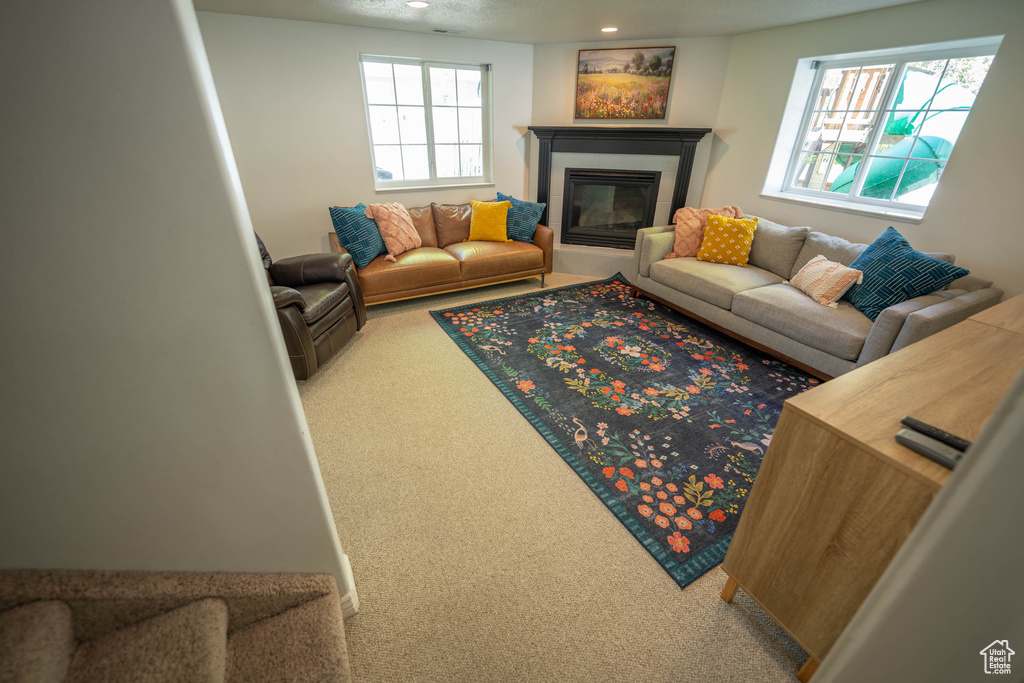 Living room featuring carpet flooring, a tiled fireplace, and recessed lighting