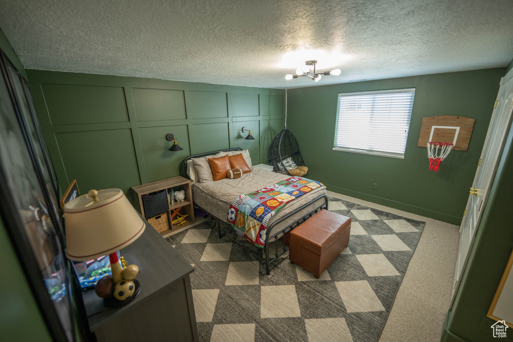 Bedroom featuring a decorative wall, a textured ceiling, and carpet flooring