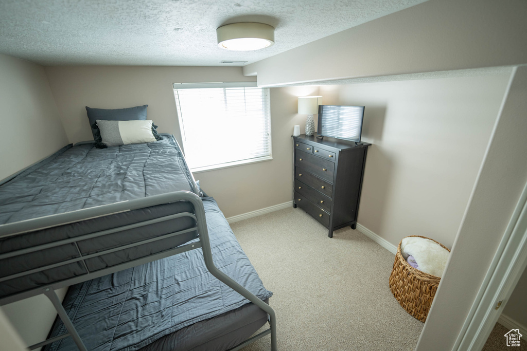 Bedroom featuring light colored carpet, a textured ceiling, and baseboards
