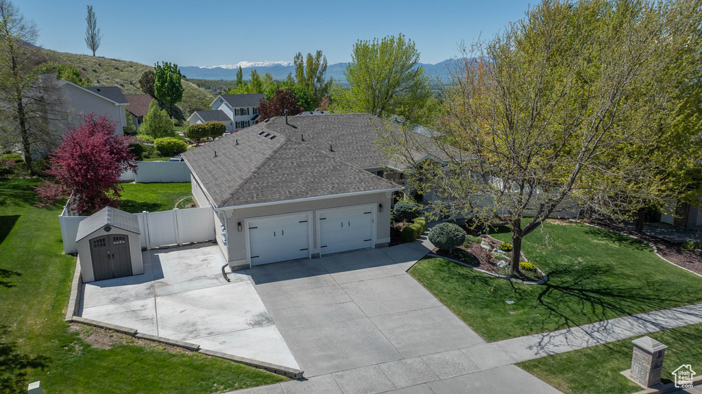 View of front of home with a garage, concrete driveway, roof with shingles, and a mountain view