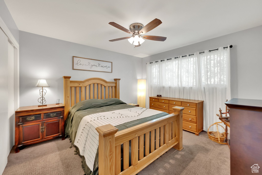 Bedroom with light colored carpet, a ceiling fan, and a closet
